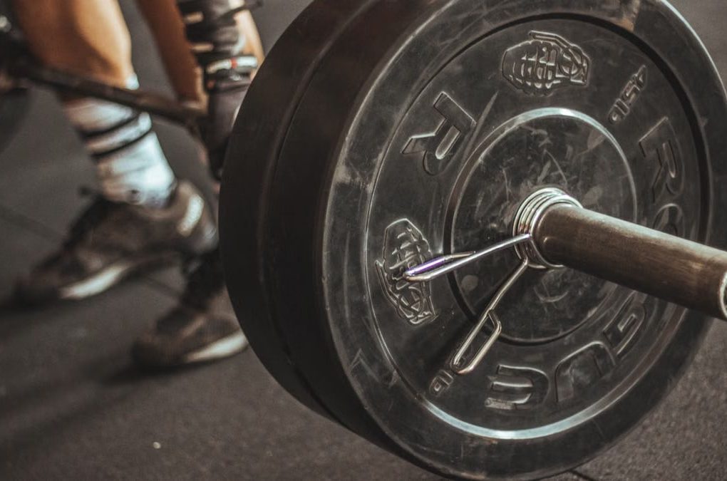 Close-up of a weightlifter's legs and barbell during a workout session.